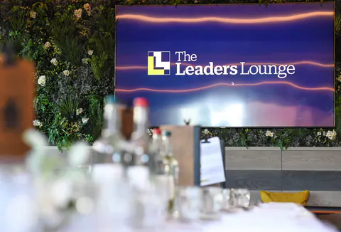 The Leaders' Lounge logo on the screen above the laid dinner table.