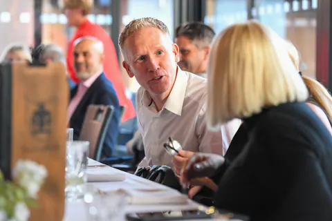A guest leaning in to make a point across the table.