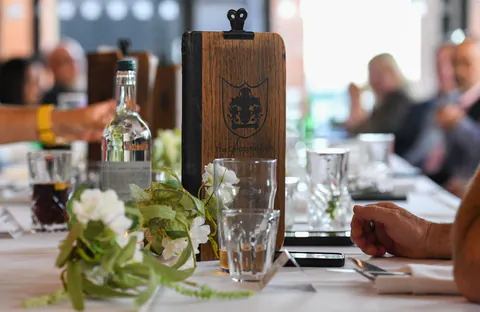 A carved wooden menu board and white flowers on the dinner table.