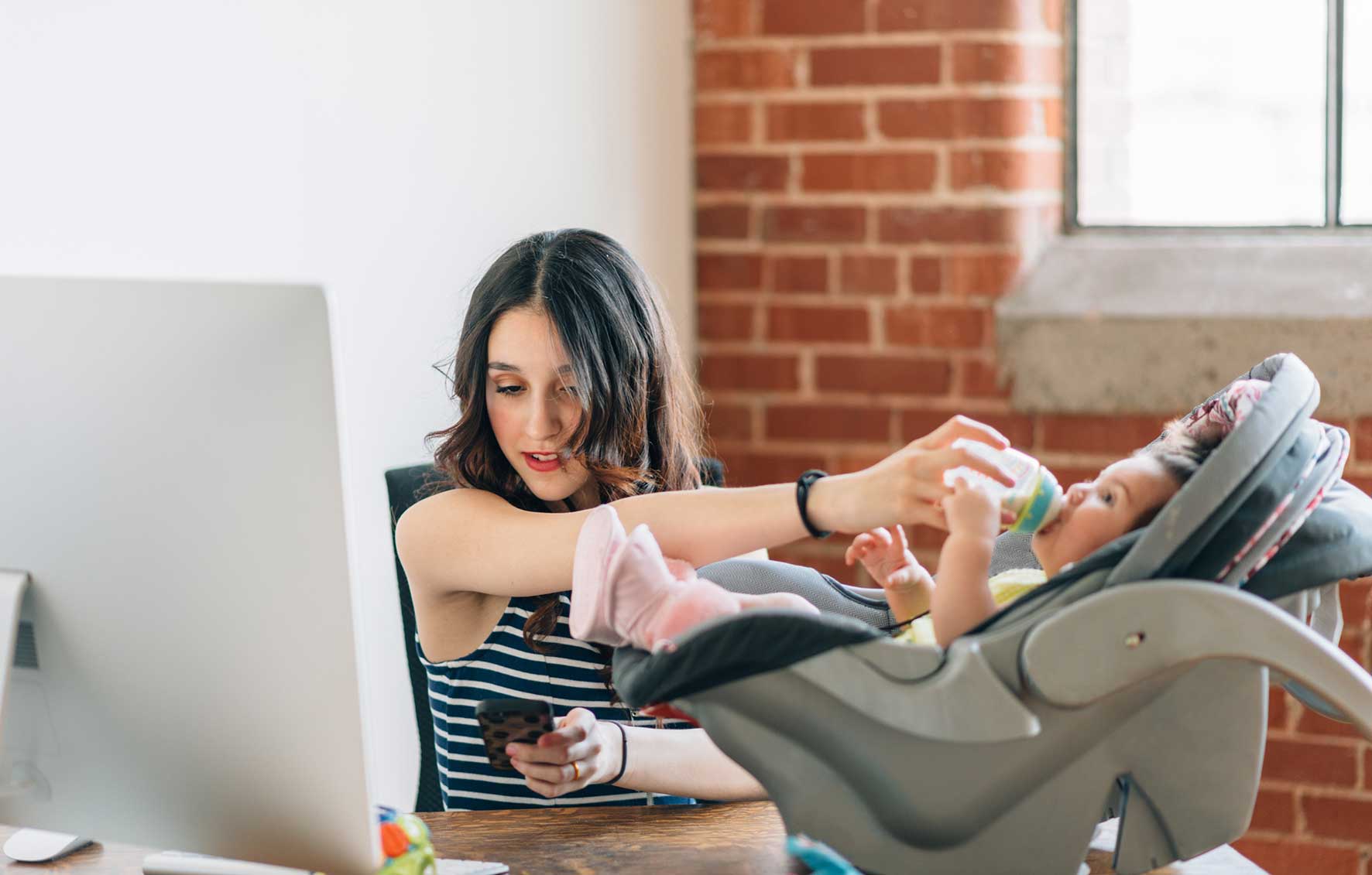woman feeding baby and working