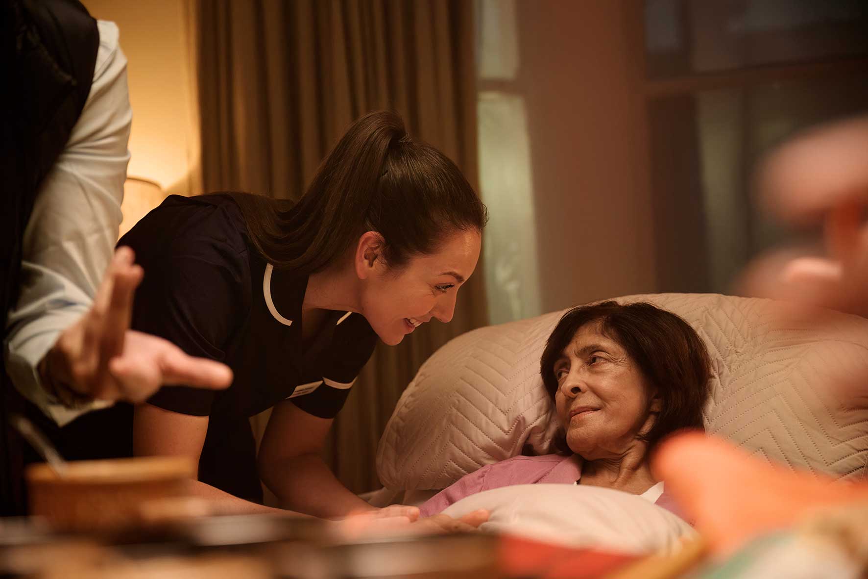 Patient receiving palliative care in bed with a Willen Hospice nurse providing bedside support.