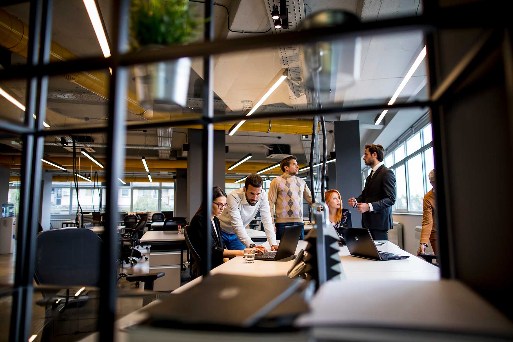 Employees working in a modern office using laptops and digital communications technology.
